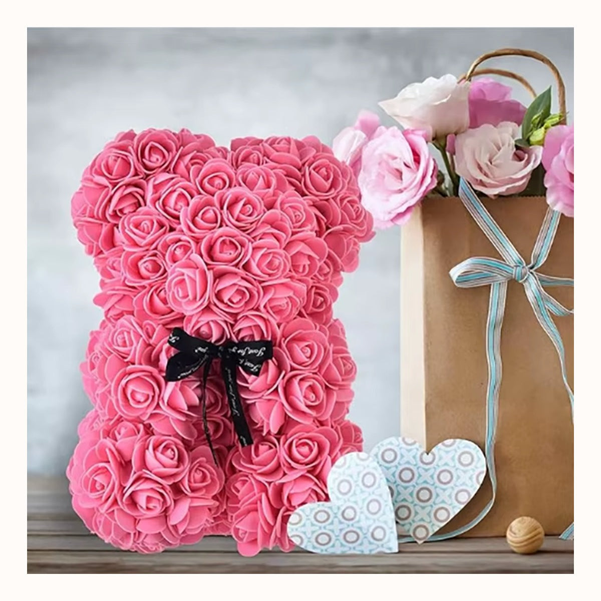 Rose bear beside a gift bag and fresh roses